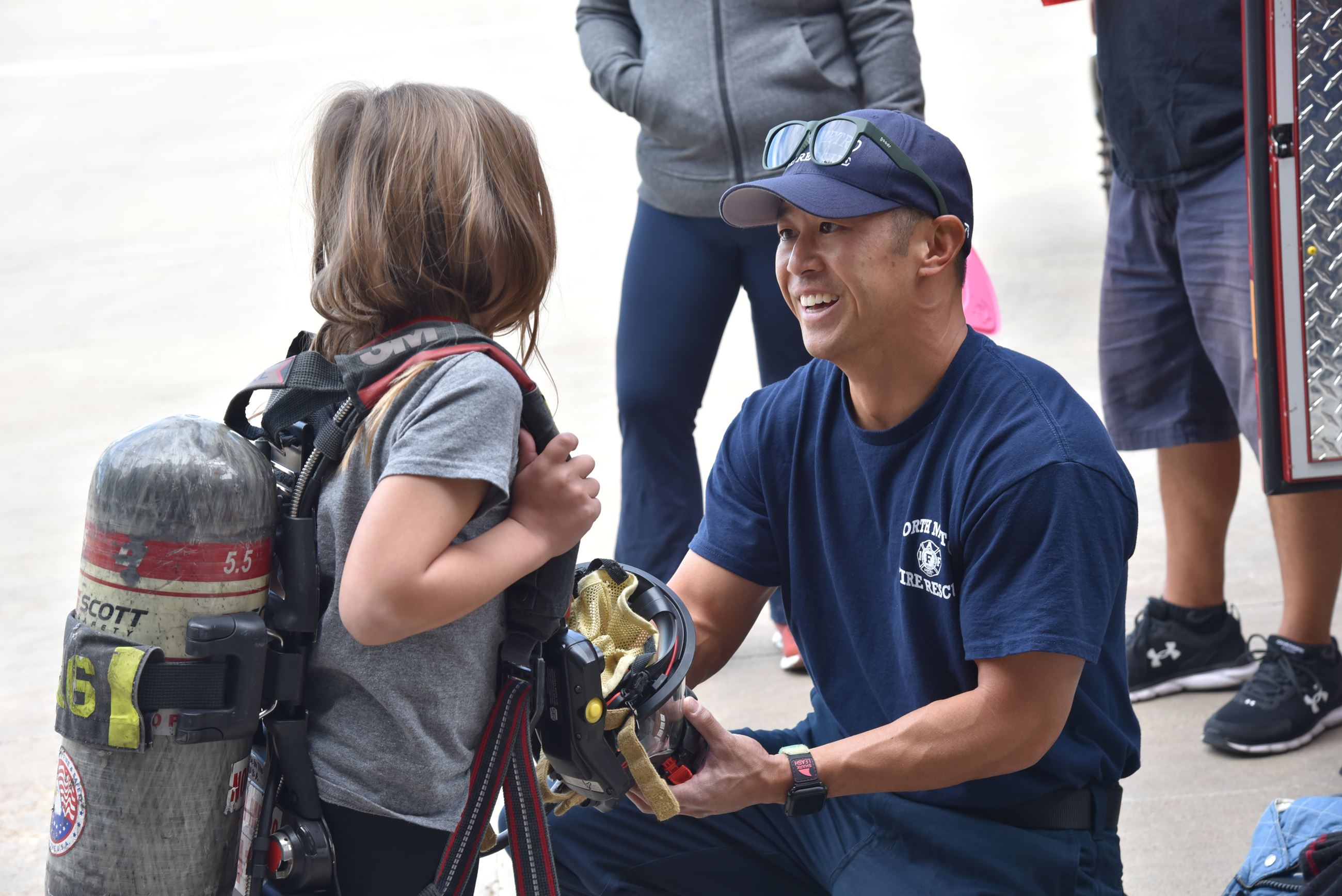 A firefighters shows a young girl the breathing mask they use when fighting fires