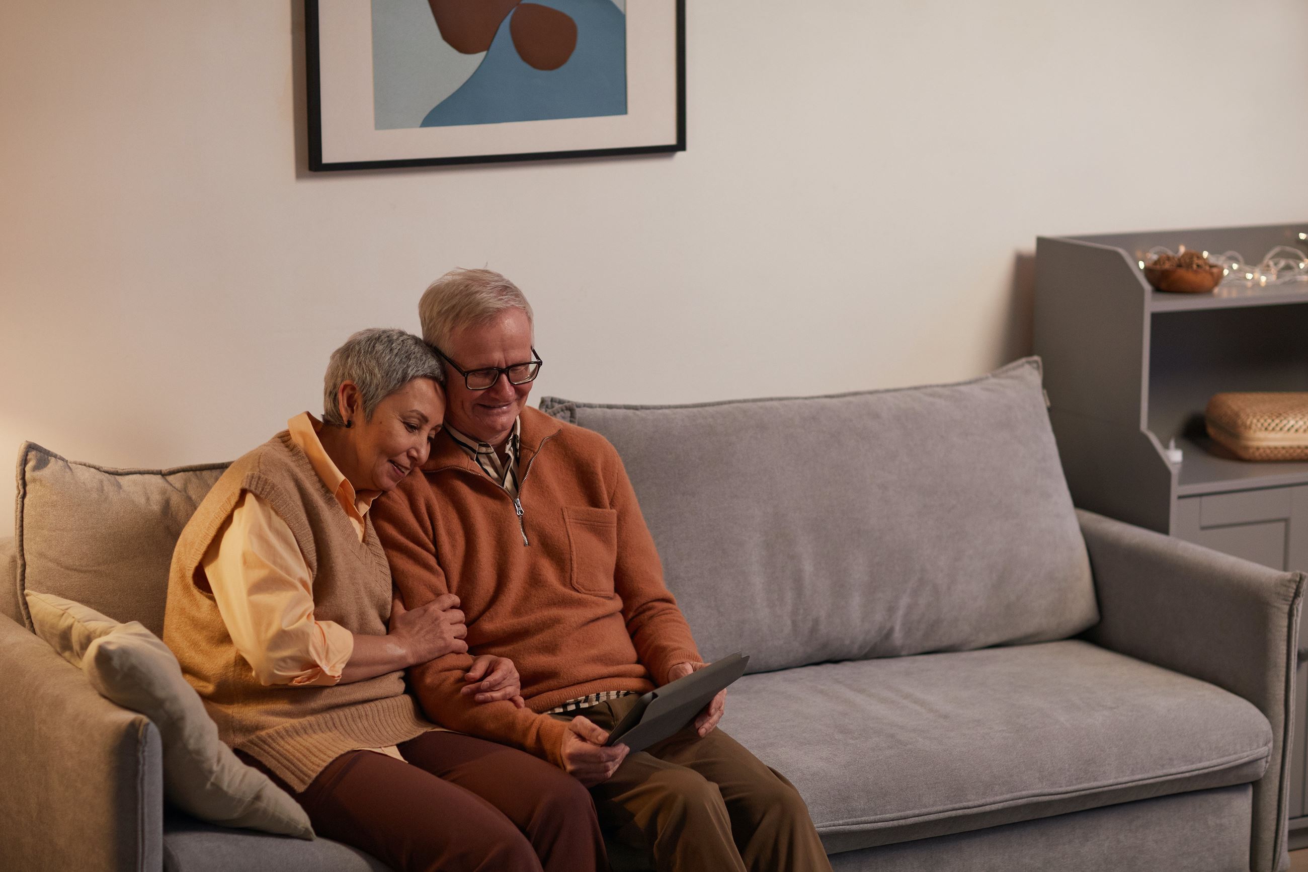 Senior couple sitting on a sofa looking at a tablet device.