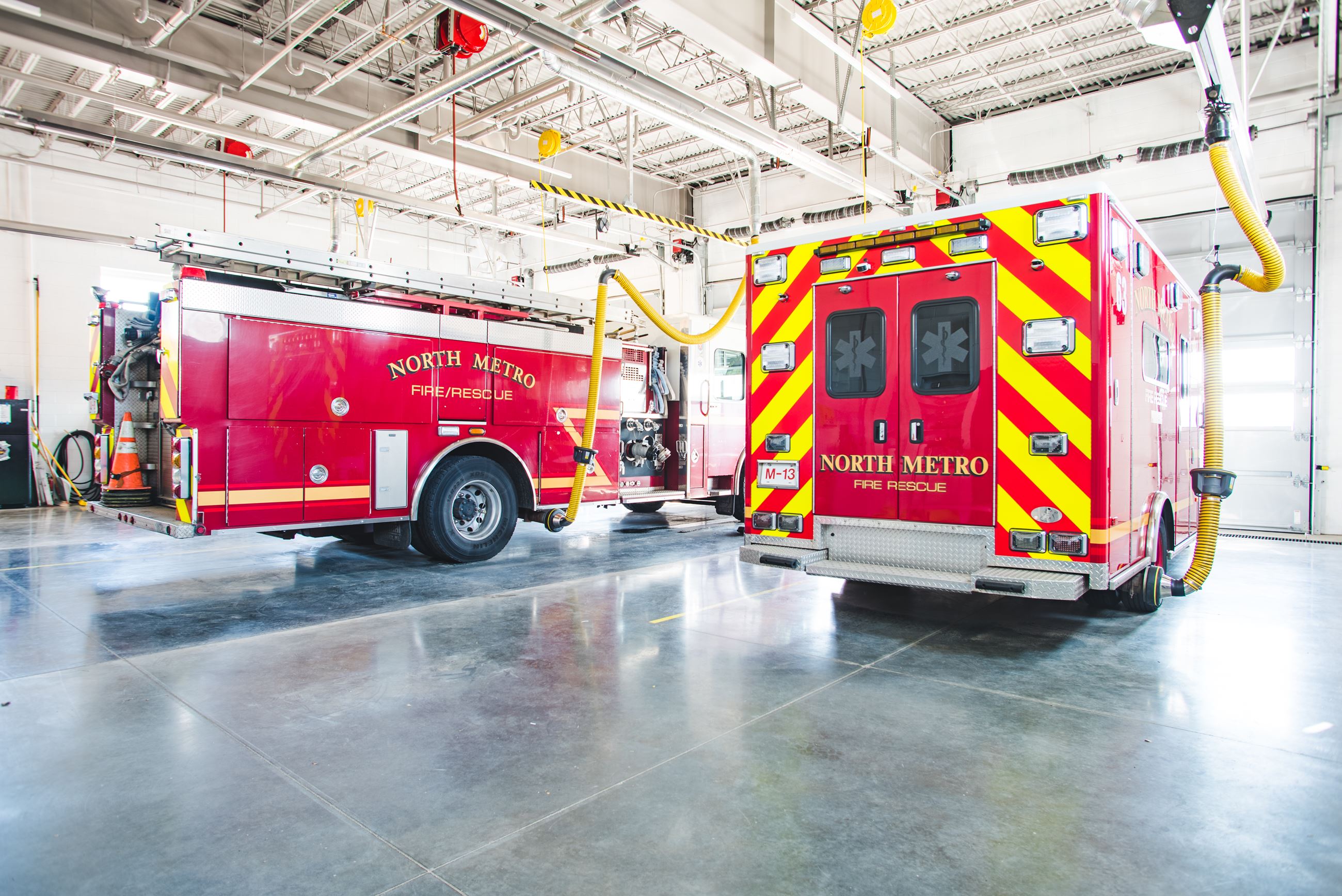 Inside a North Metro Fire station apparatus bay housing a red fire engine and an ambulance