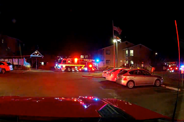 image of a fire engine in front of a building with its lights on in a parking lot at night
